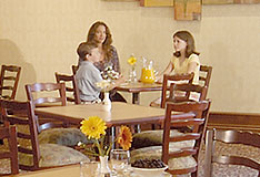 This picture shows three people sitting at a breakfast table in the dining area